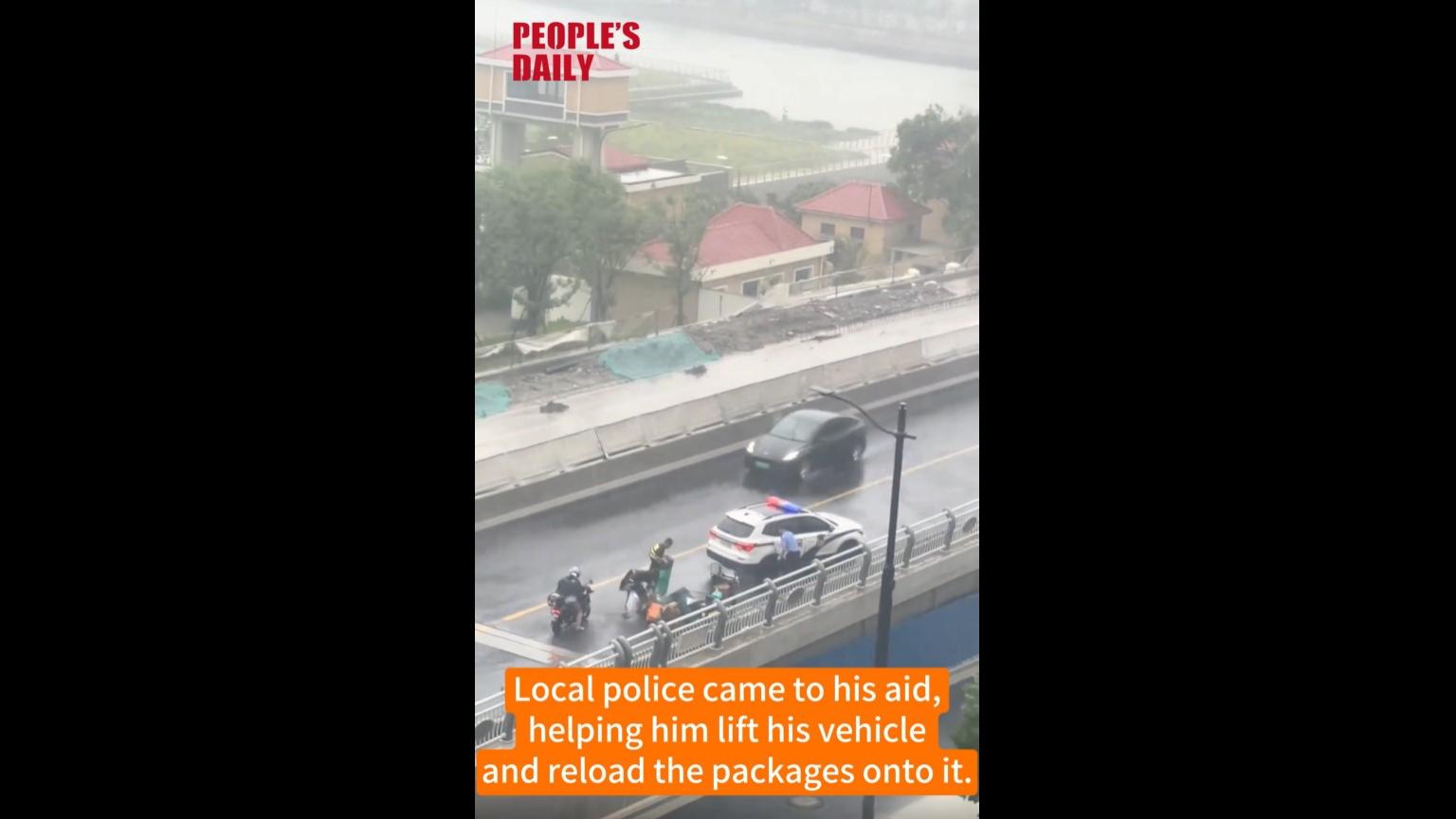 Shanghai police aids courier during typhoon